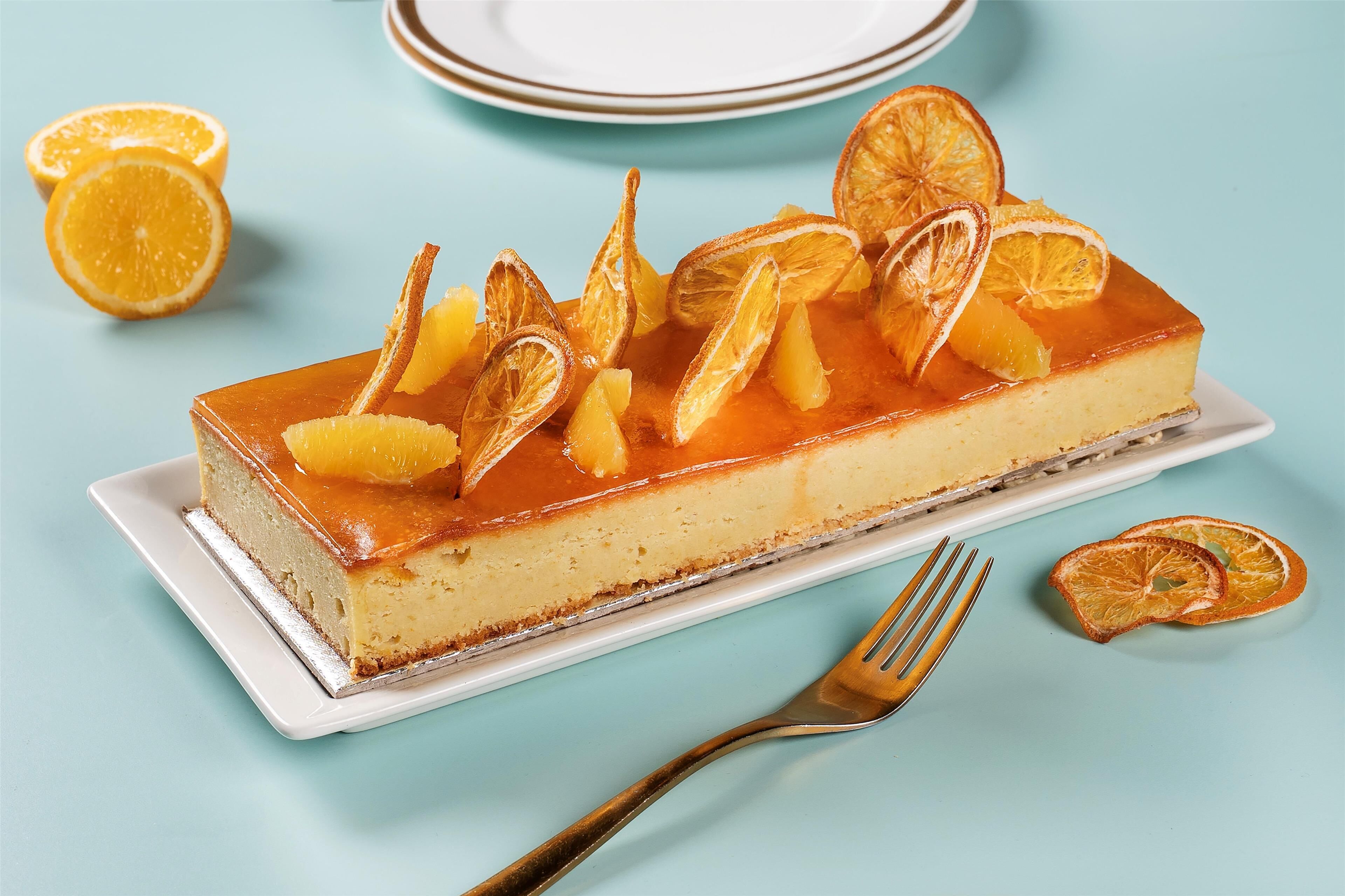 A cheesecake with dried orange slices on top, placed on a white plate.