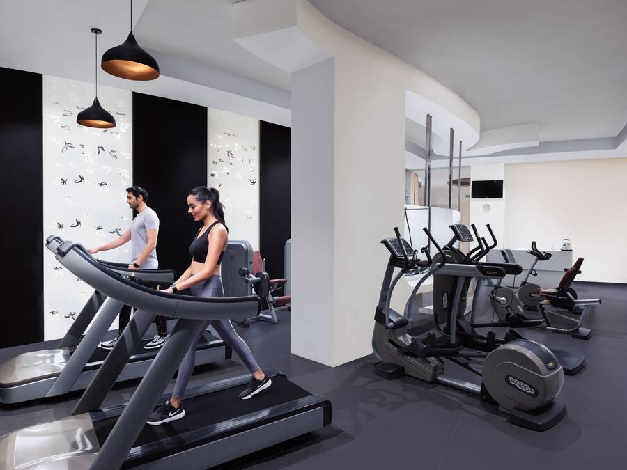 Een moderne sportschool met loopbanden, elliptische trainers en gewichttoestellen.