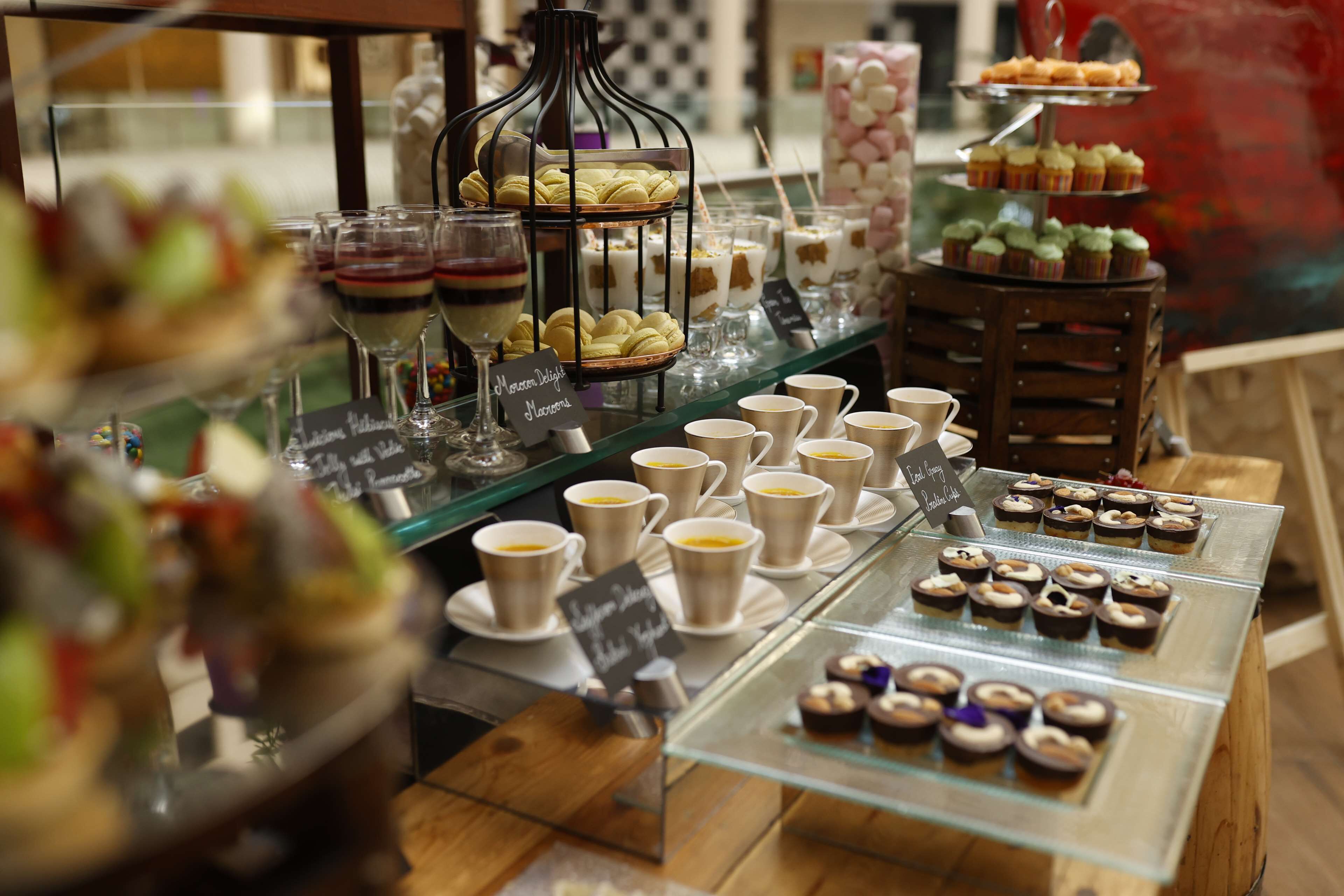Une vitrine de boulangerie présentant une variété de pâtisseries et de desserts, notamment des macarons et des cupcakes, disposés sur des étagères et dans des présentoirs en verre.