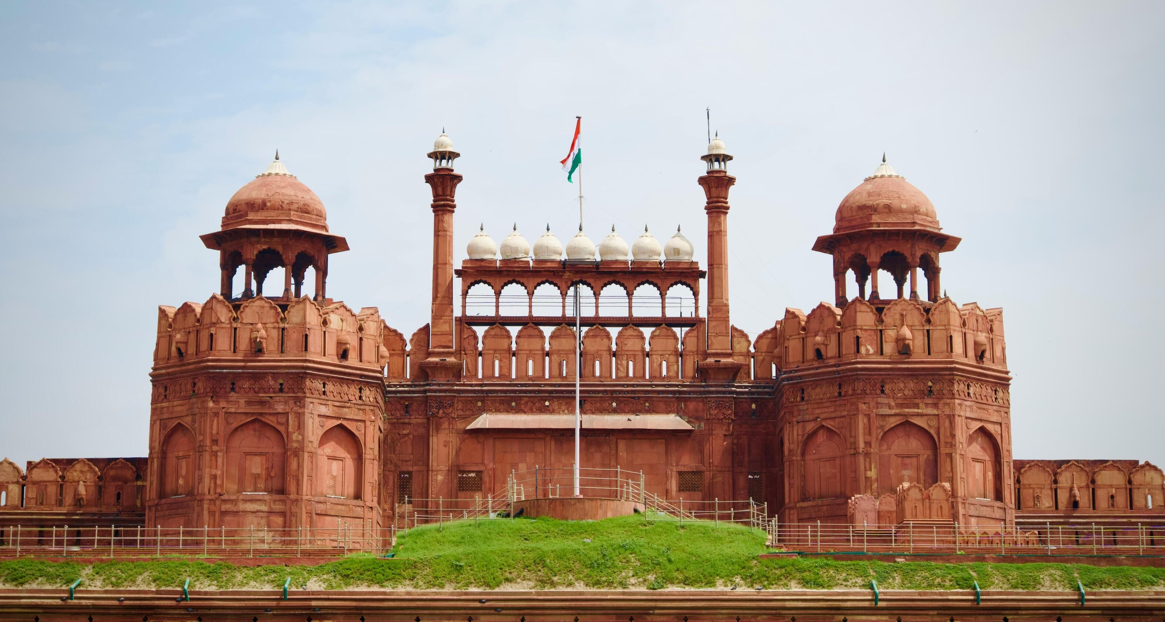 A large, historic building with two prominent domes and a central tower, featuring intricate architectural details and a flag.