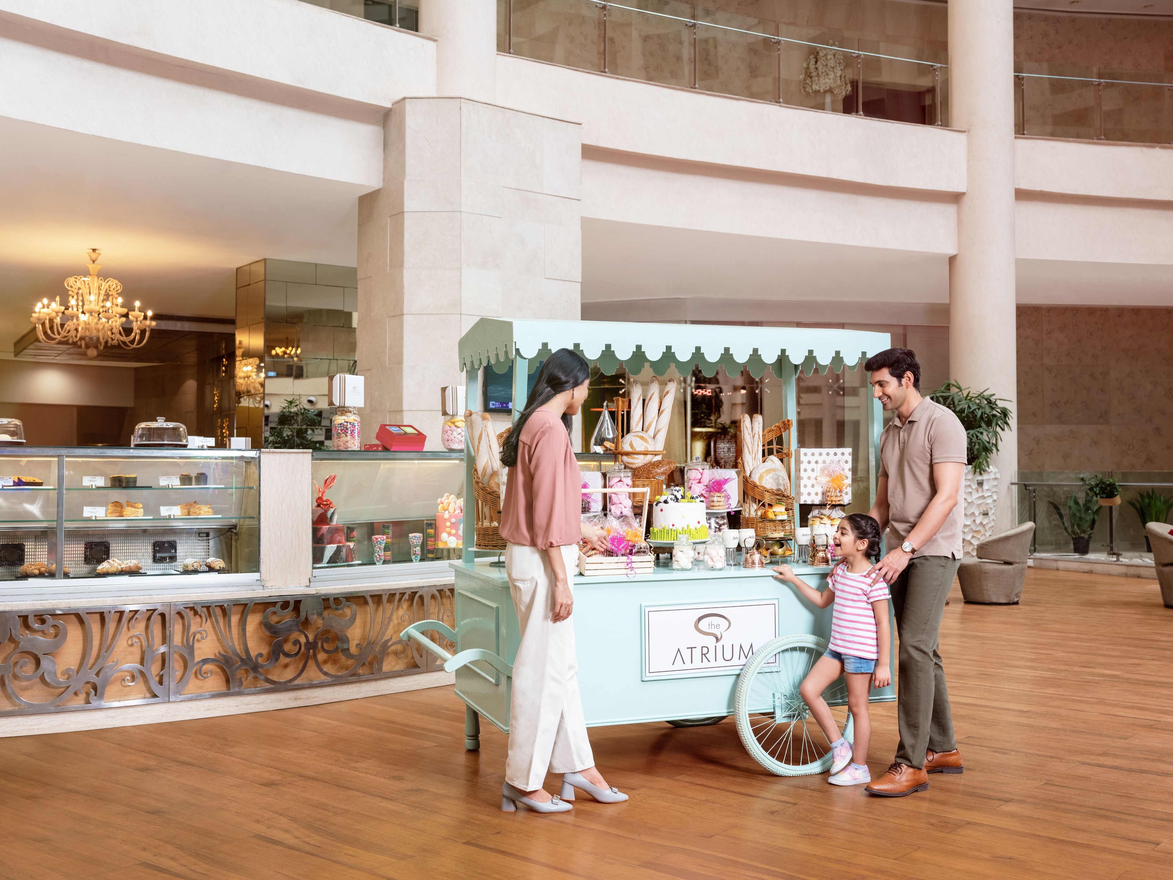 A kiosk with a sign reading "The Atrium" in a spacious indoor area with a high ceiling and wooden flooring.