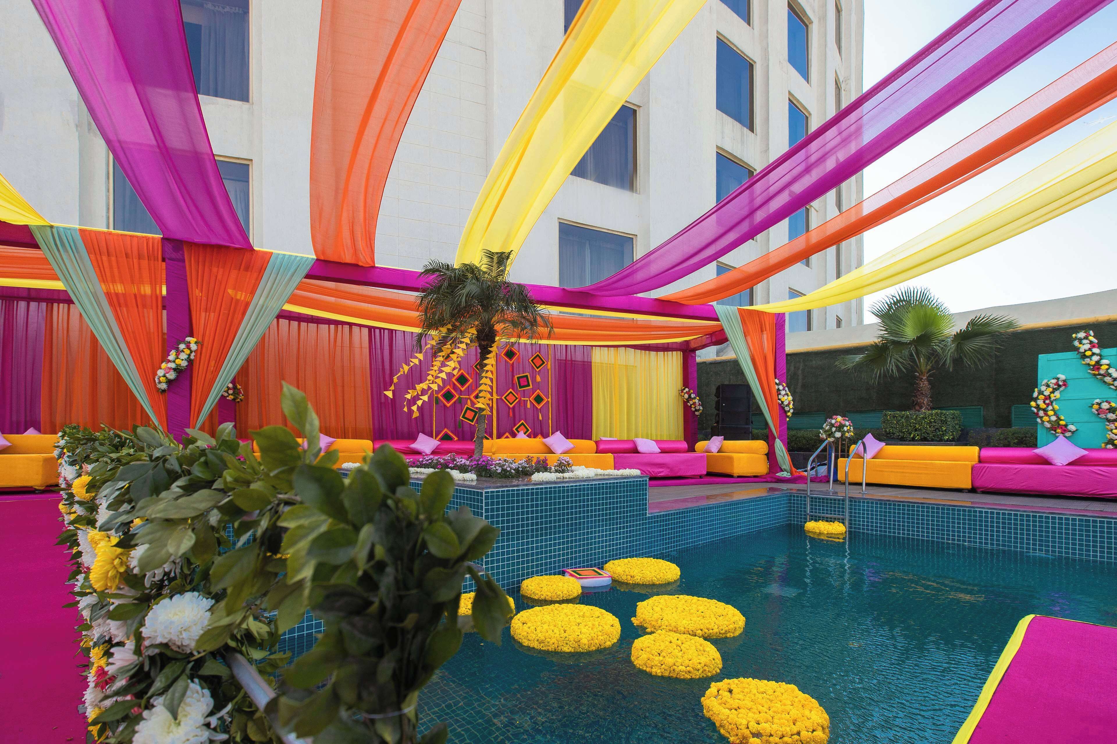 Un espace piscine agrémenté de tentures colorées et de compositions florales.