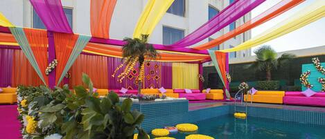 Un espace piscine agrémenté de tentures colorées et de compositions florales.