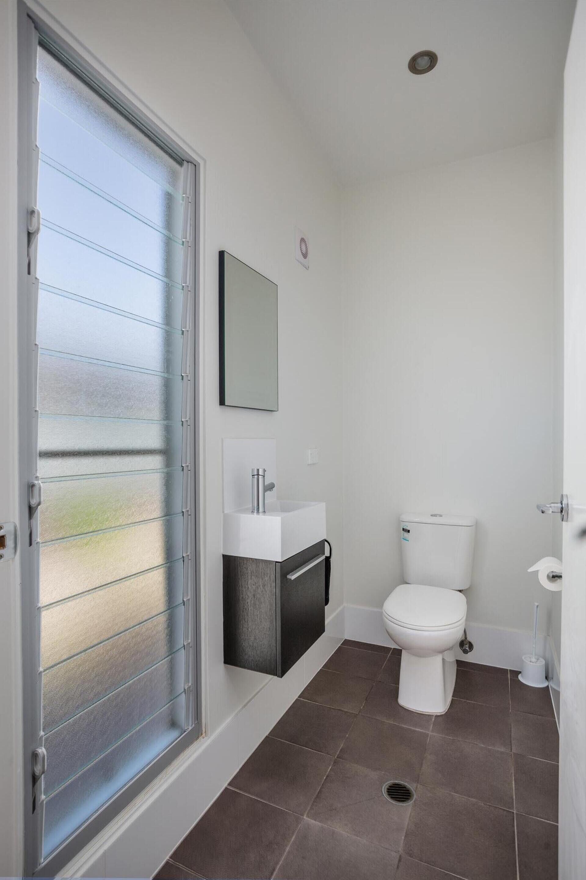 A bathroom with a toilet, sink, and frosted glass door.