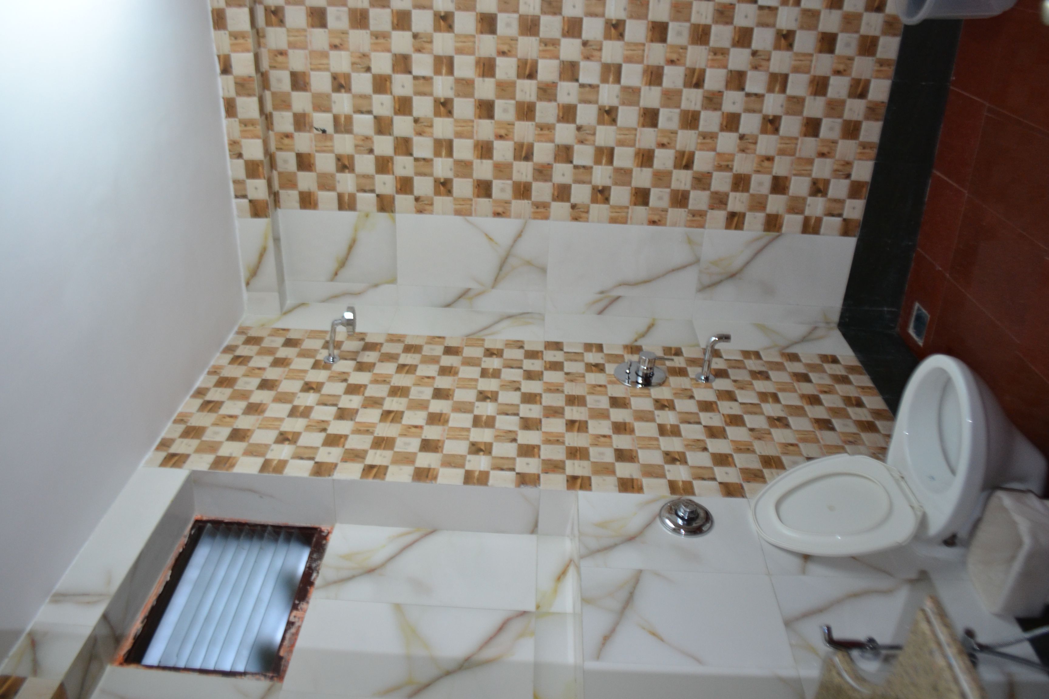 Une salle de bain avec un mur recouvert de carreaux à motifs géométriques, un meuble-lavabo en marbre et des toilettes.