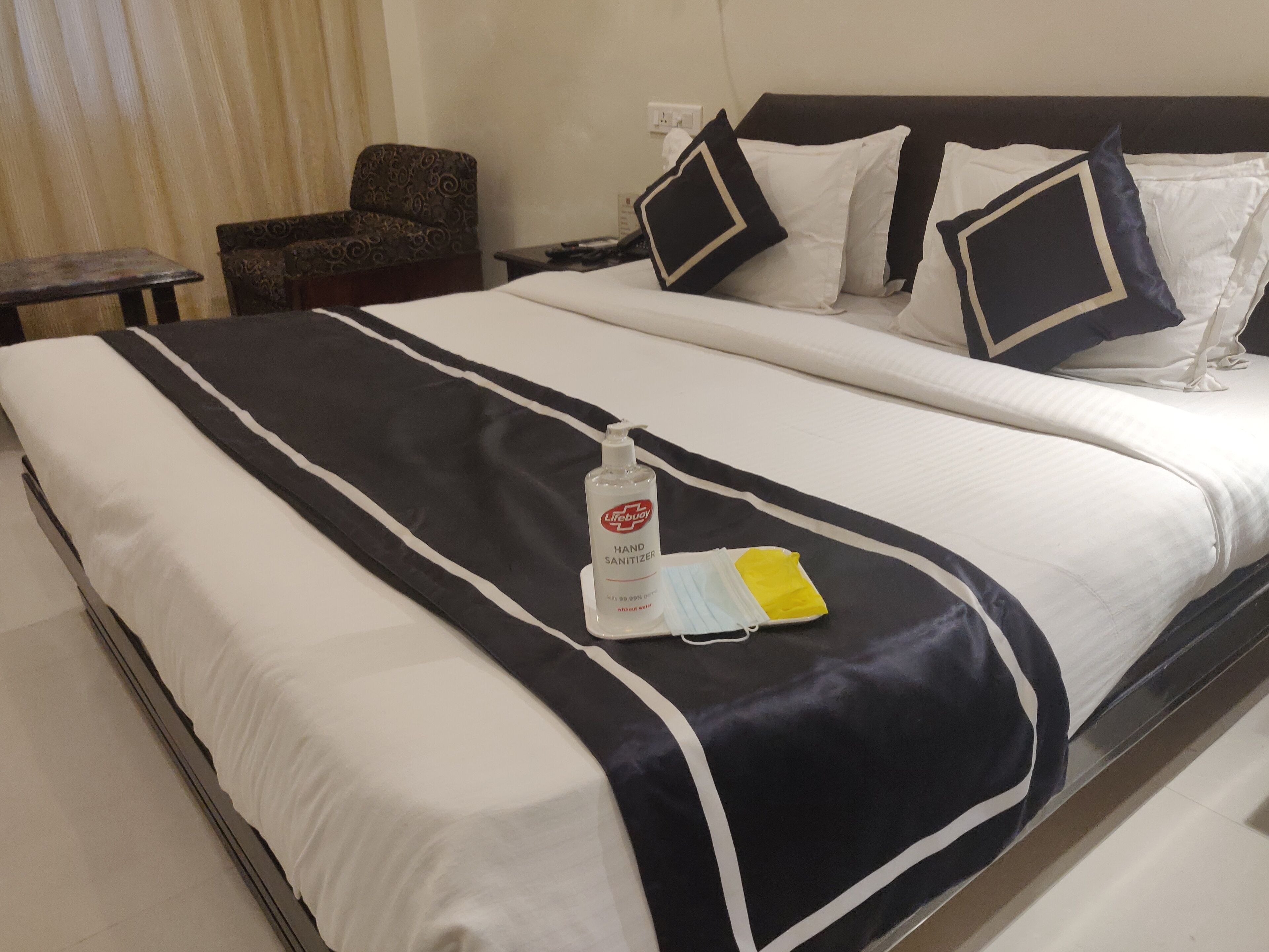 A hotel room with a neatly made bed, a bedside table, a chair, and a nightstand.