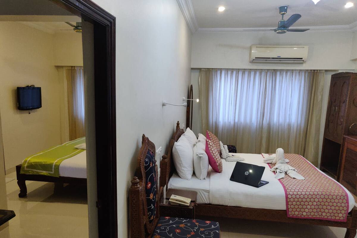 Habitación de hotel con cama, escritorio, silla, aire acondicionado y televisor.