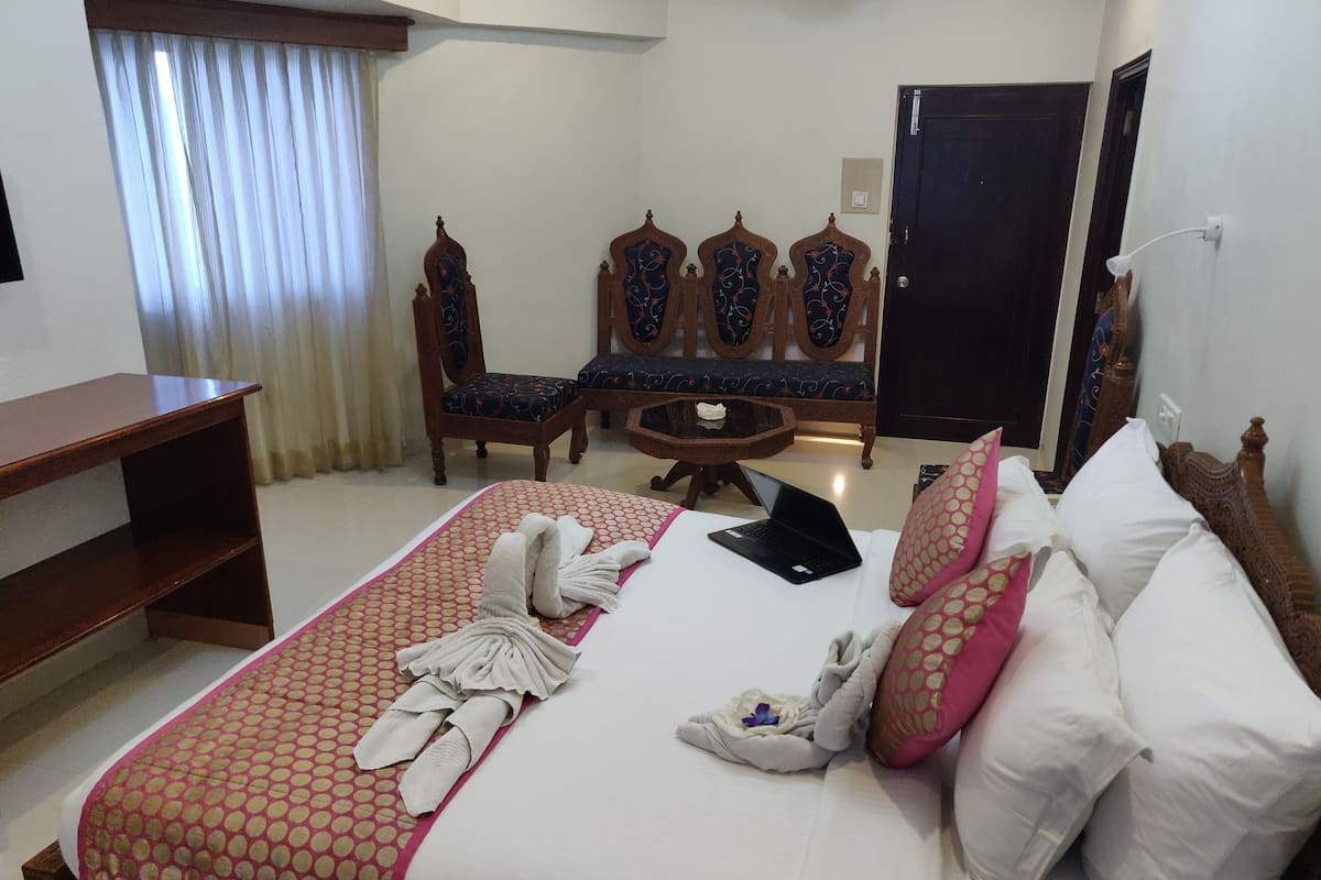 A hotel room with a neatly made bed, a laptop, and a small round table.