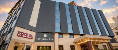 A hotel with a modern facade, a restaurant on the ground floor, and a well-lit entrance.