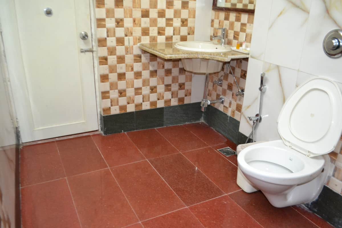 A bathroom with a checkered tile wall, a sink, and a toilet.