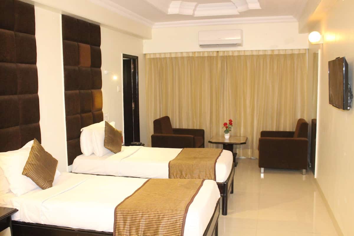 A hotel room with two beds, a sofa, a small table, and a TV.