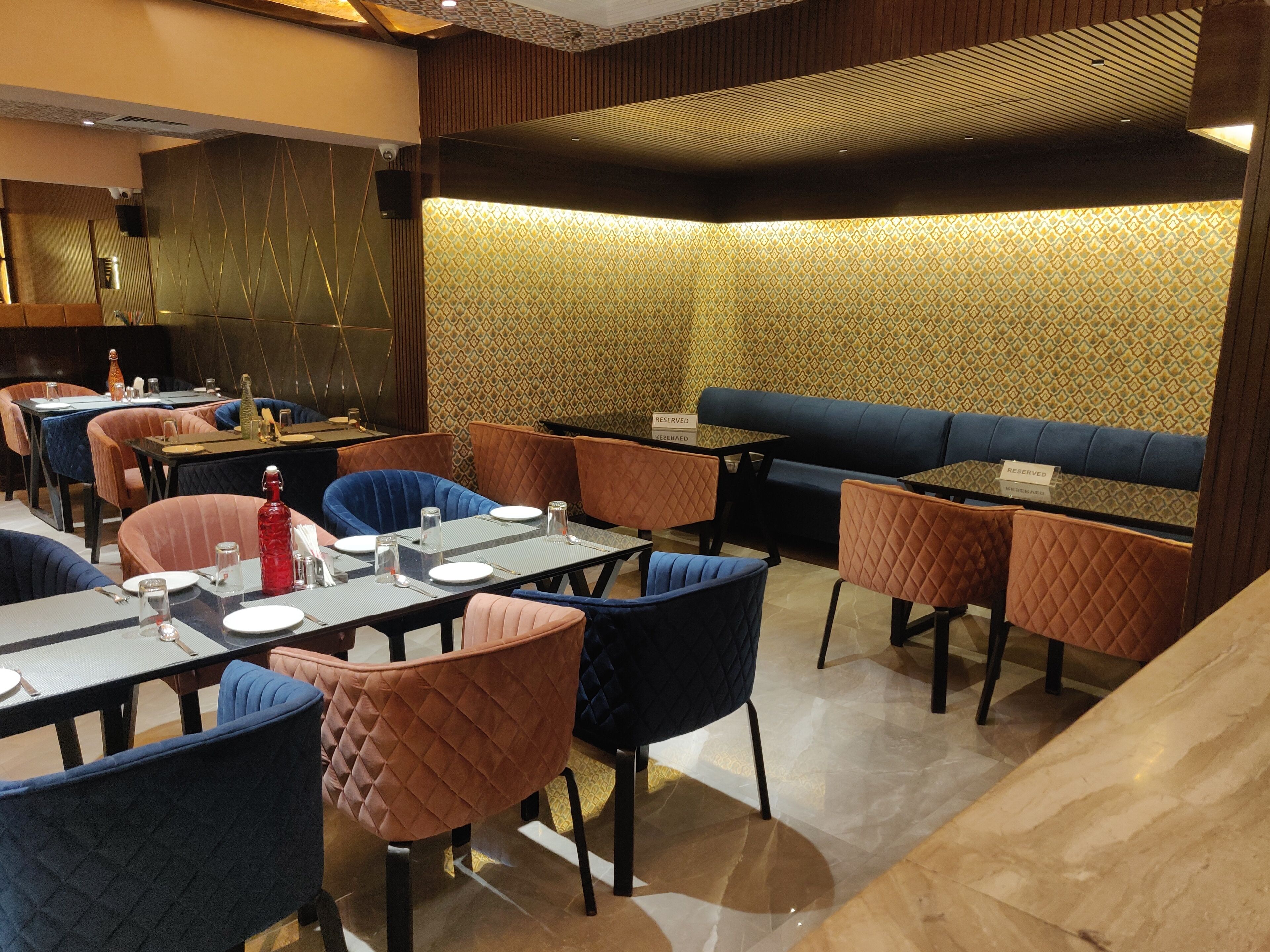 A restaurant with tables and chairs, a reserved seating area, and a patterned wall.