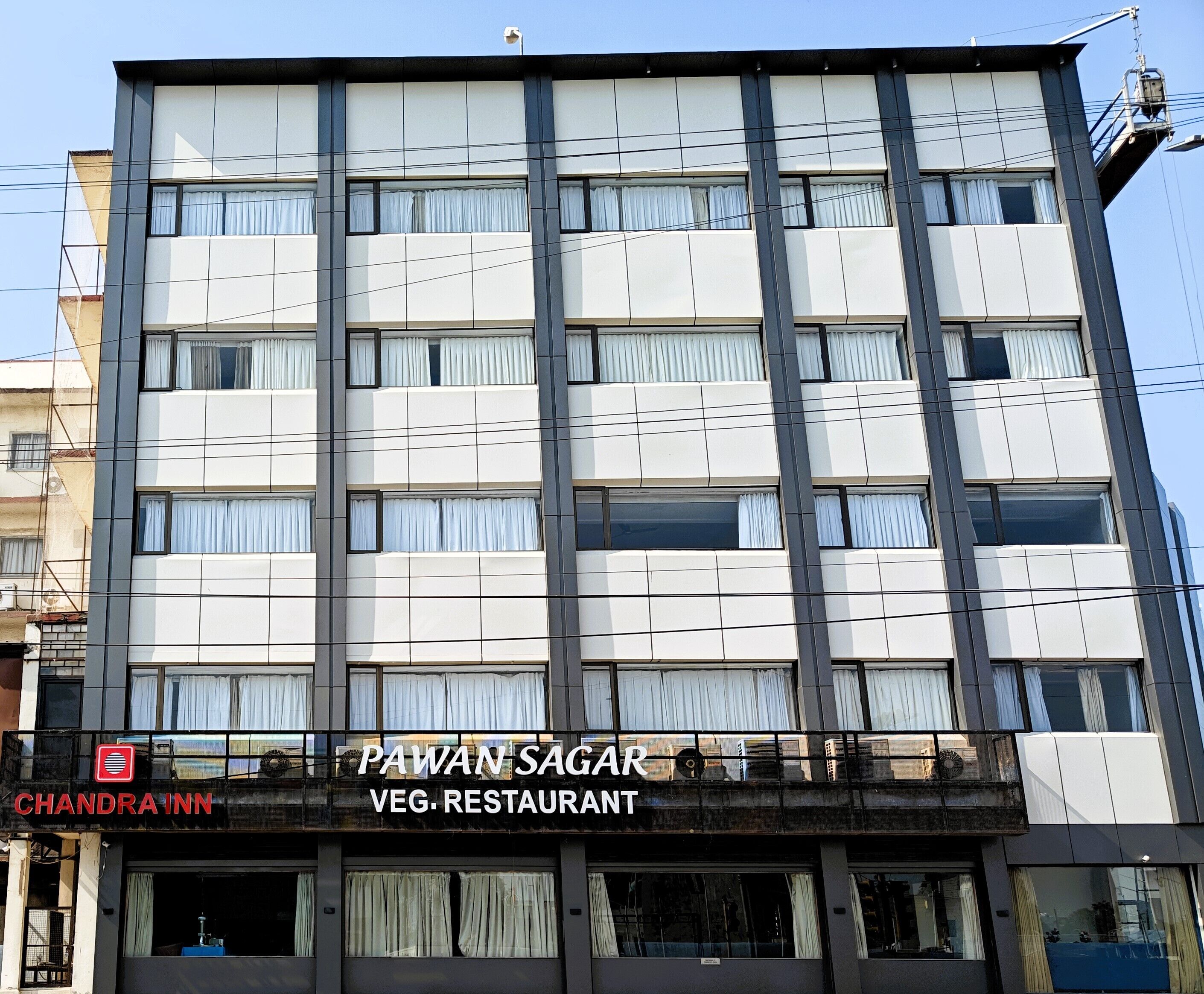 Un edificio de varios pisos con diseño moderno, que cuenta con un restaurante llamado “PAWAN SAGAR” en la planta baja.