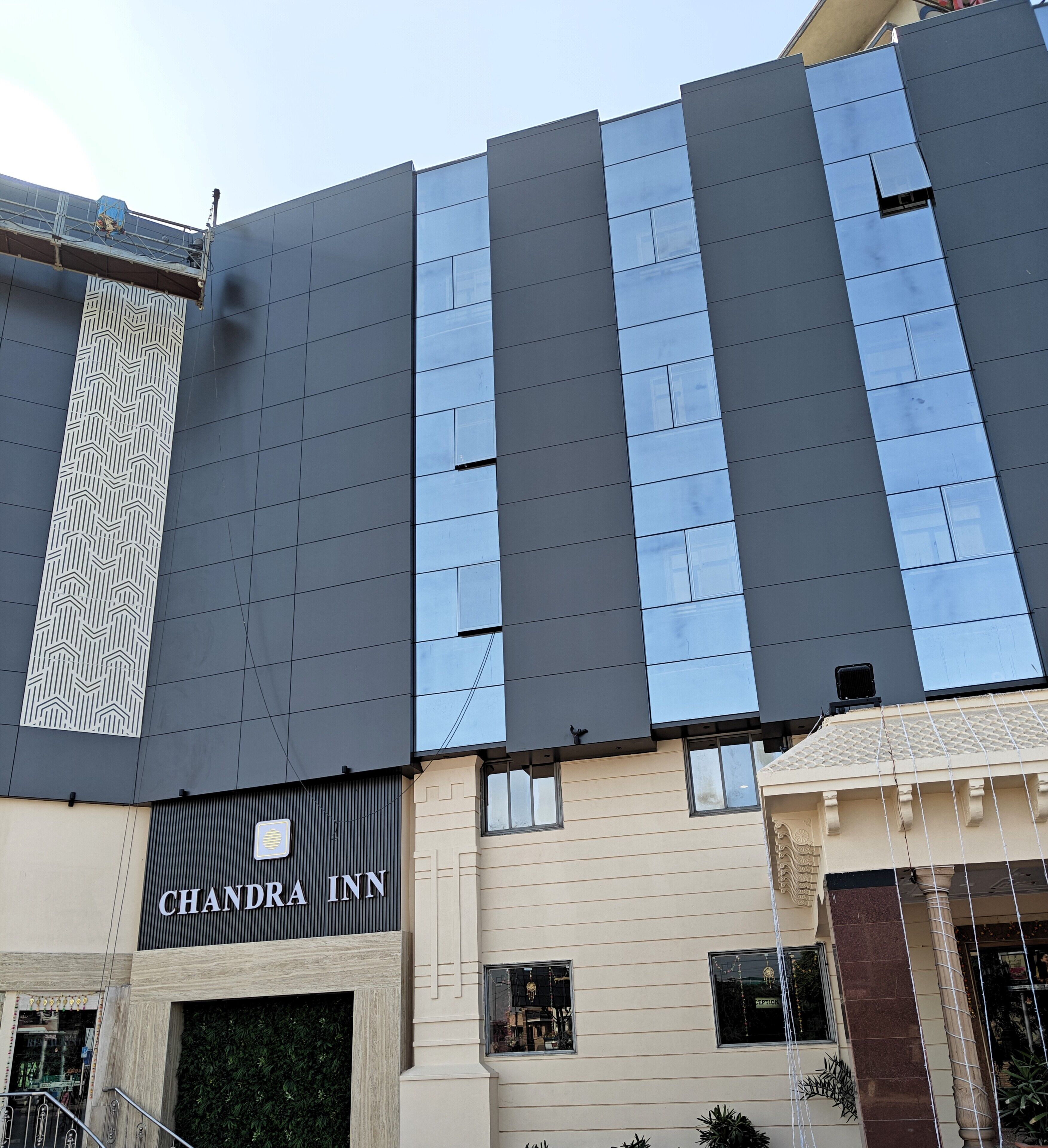 A modern building with a flat facade, a visible sign for 'CHANDRA INN', and a patterned vertical element on the left.