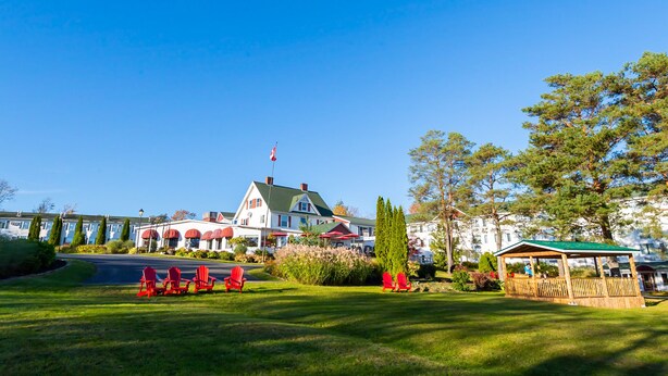 A lodge with a green roof, red chairs, and a wooden gazebo. - Auberge Gisele's Inn (Baddeck)