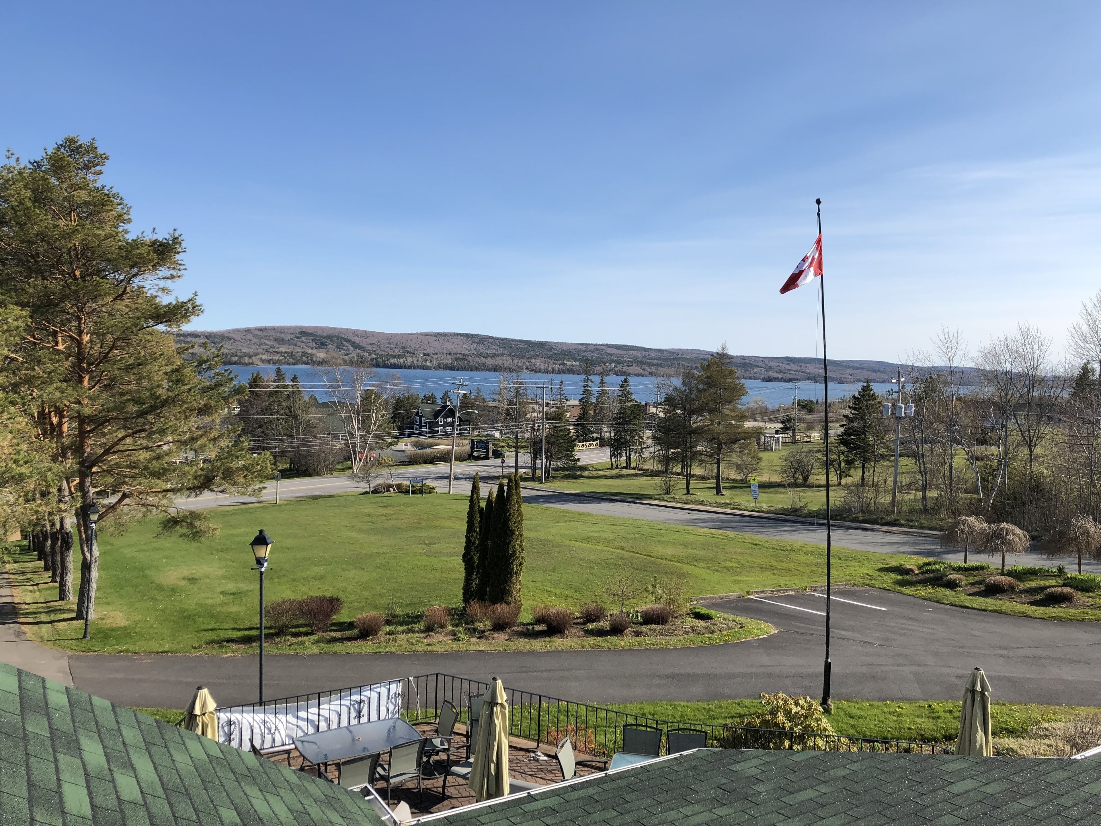 A view of a residential area with a flag, a road, and a body of water in the background.