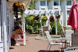 A patio area with outdoor seating, a pool, and hanging flower baskets.