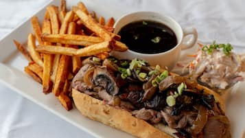 A plate of food including a sandwich, fries, and a cup of sauce.