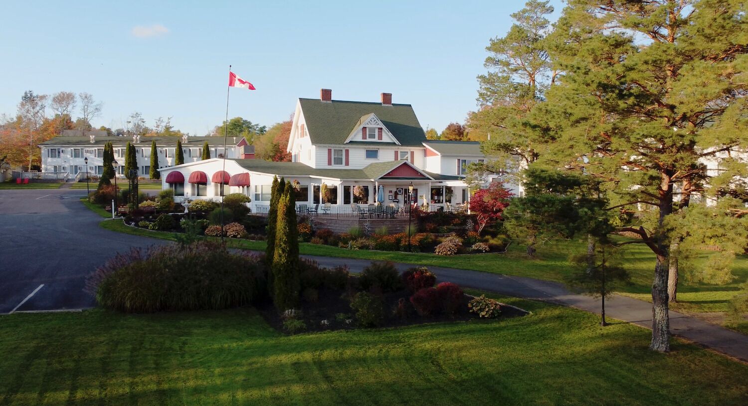 Un edificio grande de dos pisos con techo verde y fachada roja y blanca. Hay un asta de bandera con la bandera canadiense.