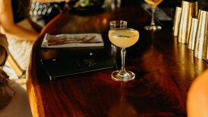 A bar area with a wooden counter, two cocktails, and a menu. - The Waves at Cane Bay (Kingshill)