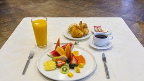 A breakfast setting with a fruit platter, croissant, coffee, and juice on a table. - Hotel del Paseo (Puebla)