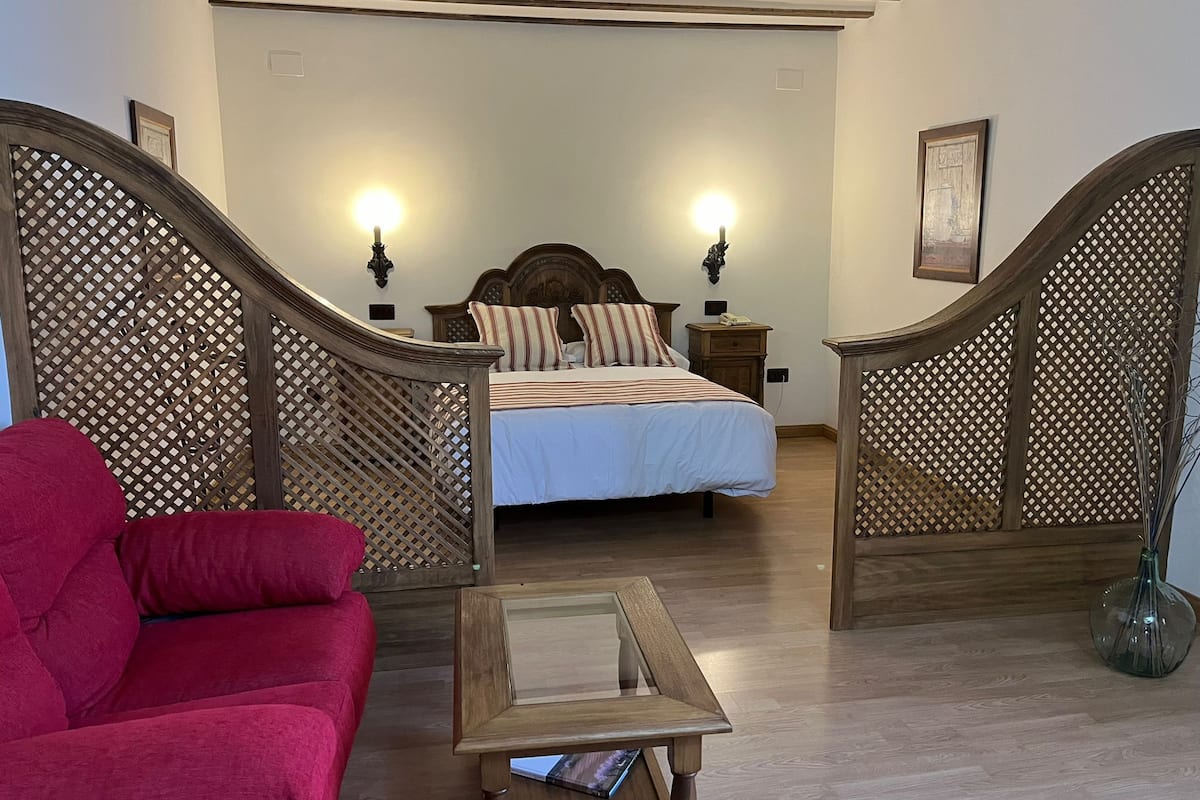 A bedroom with a bed, wooden furniture, and a staircase.