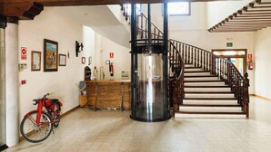 A spacious lobby with a wooden staircase, a reception desk, and a red bicycle. - Hotel A Posada (Tembleque)