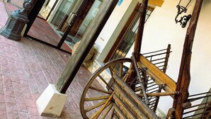 A covered outdoor area with a wooden cart and a statue. - Hotel A Posada (Tembleque)
