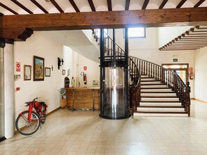 A spacious lobby with a wooden staircase, a reception desk, and a red bicycle.