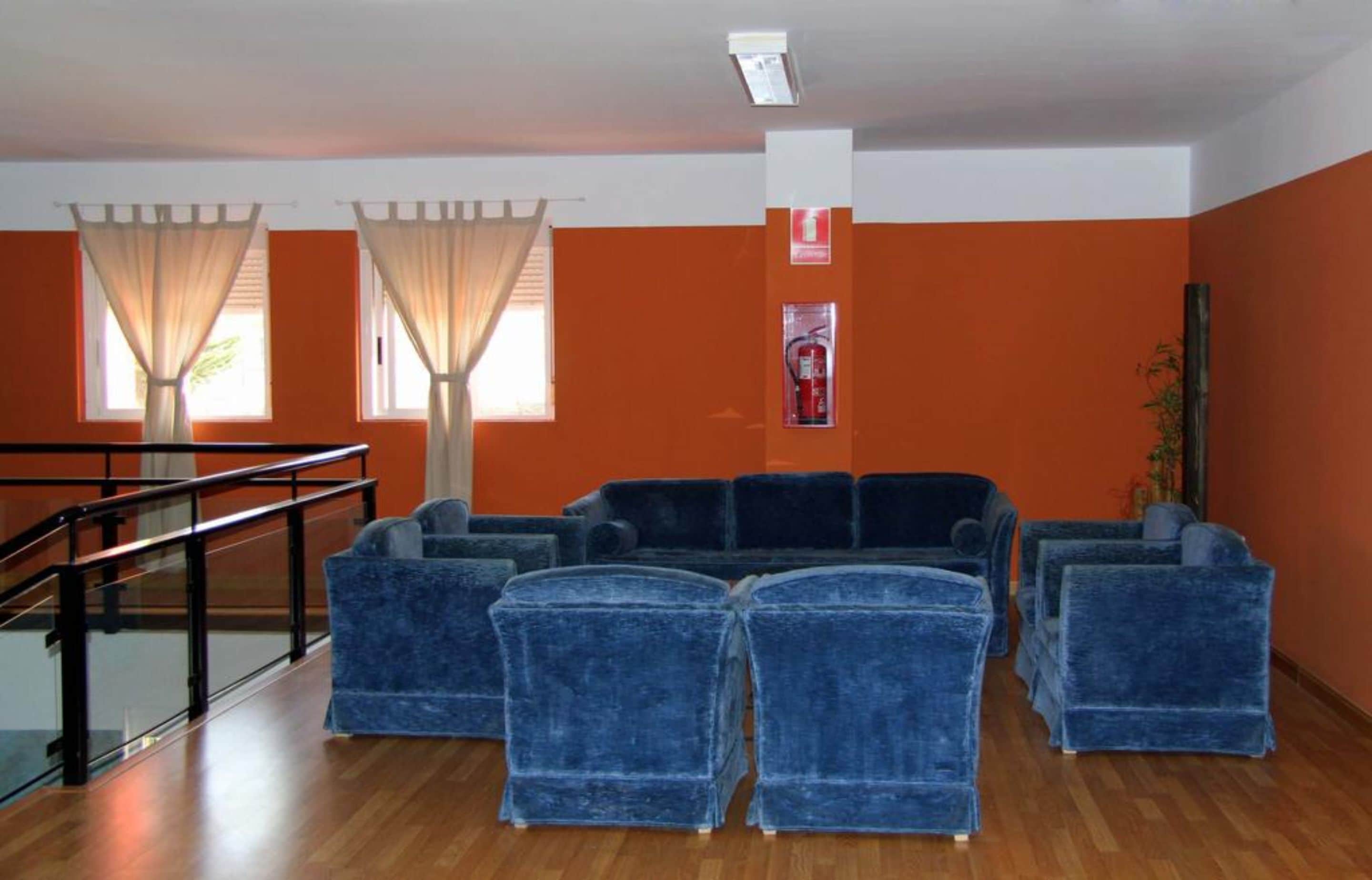 A lobby with a blue sofa set, a staircase, and orange walls.