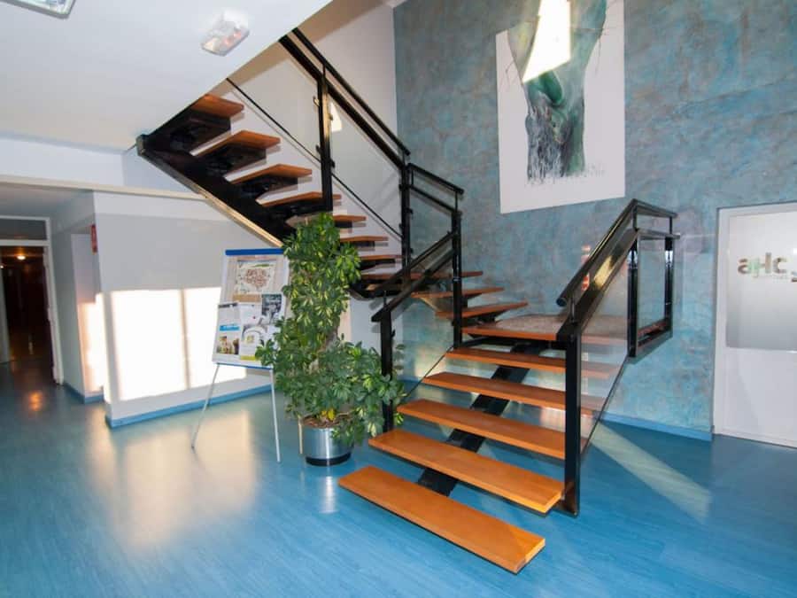 Un interior moderno con una escalera, una planta en maceta y un cartel en la pared.