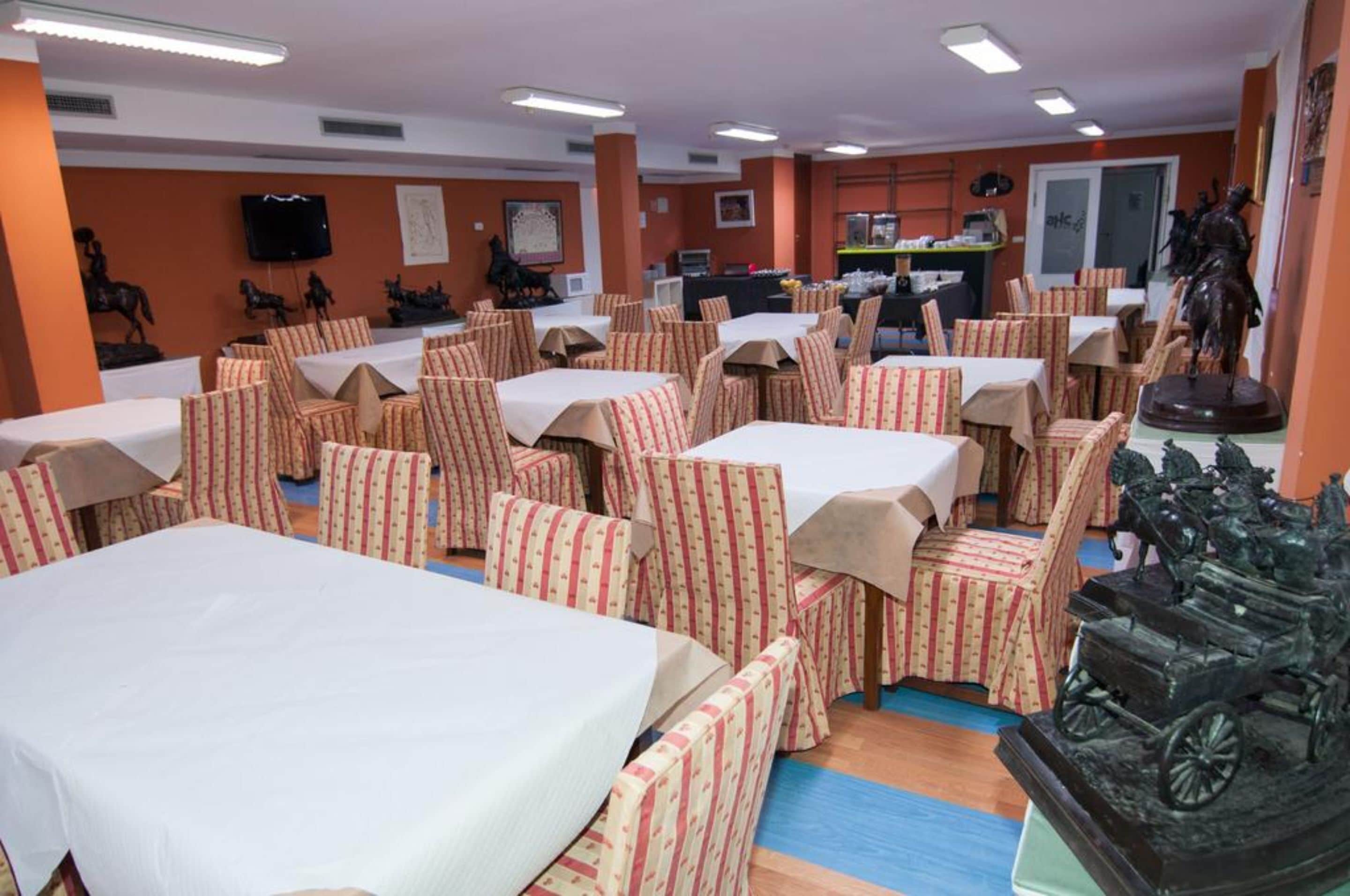 A dining area with tables and chairs, a television, and decorative statues.