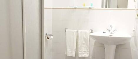 A bathroom with a toilet, sink, and mirror.