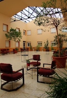 A spacious indoor area with multiple seating arrangements, including chairs and sofas, and several potted plants.