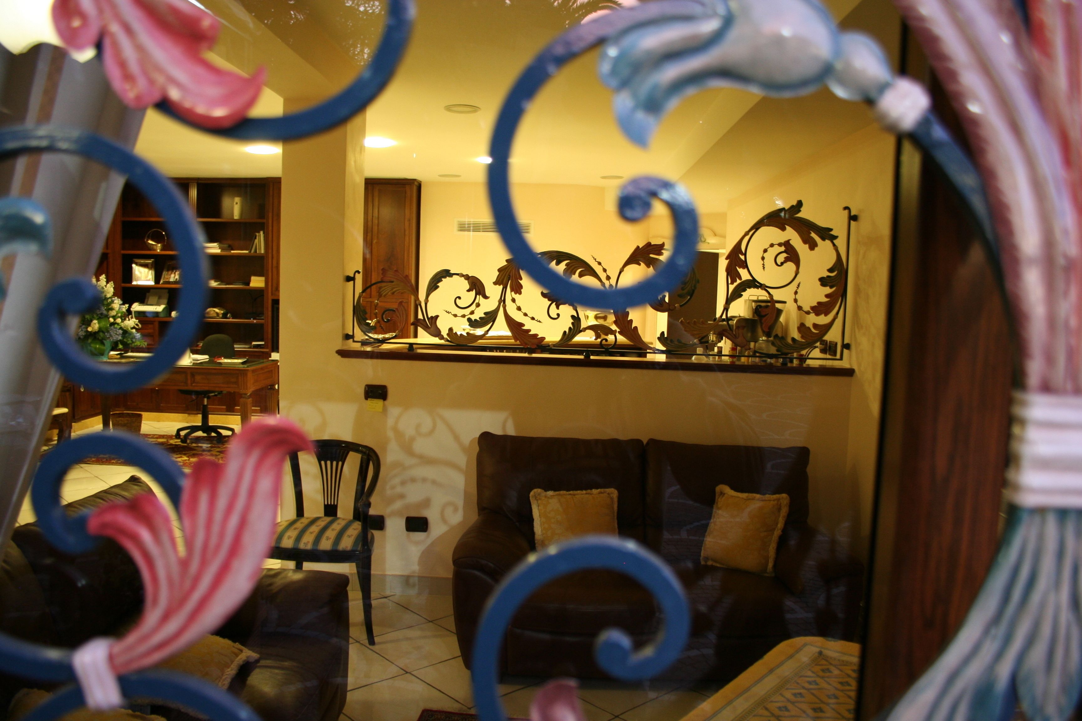 A living room with a sofa, chairs, and a decorative metal piece above the sofa.