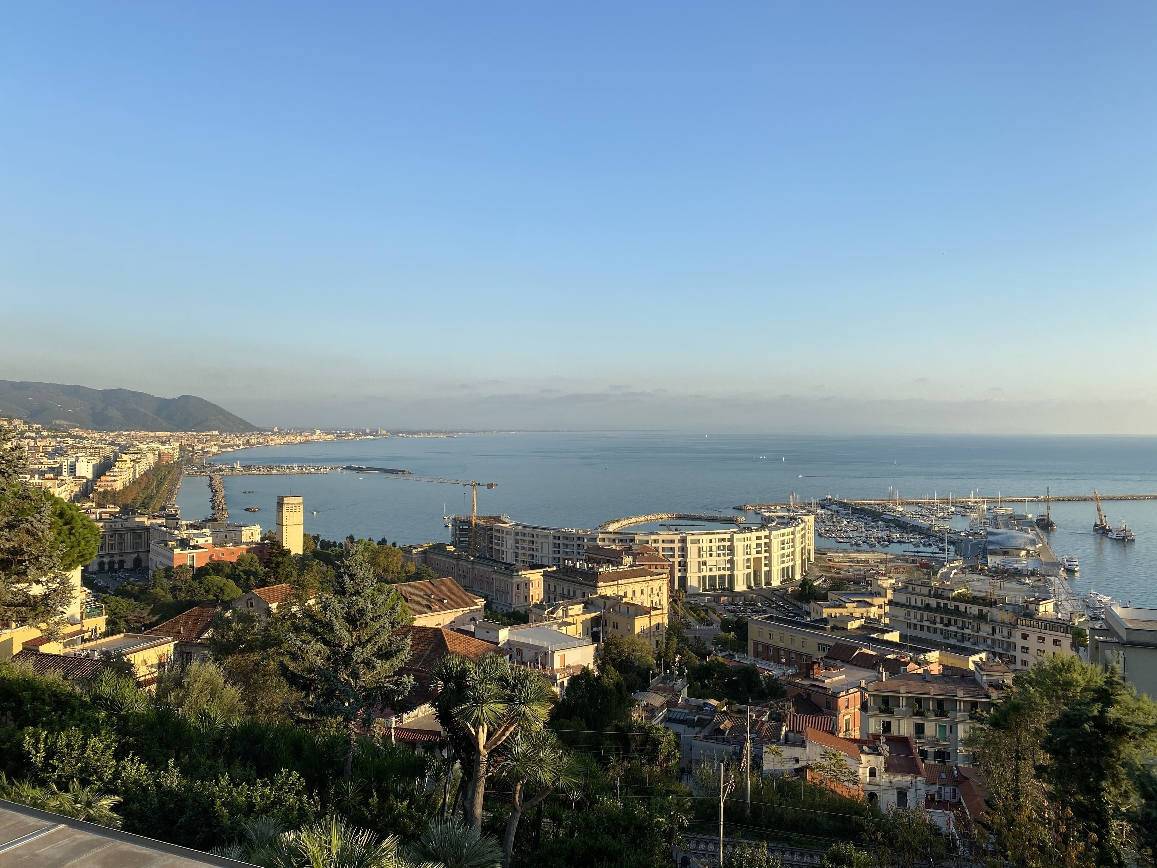 Paisagem costeira com um porto, edifícios e céu limpo.