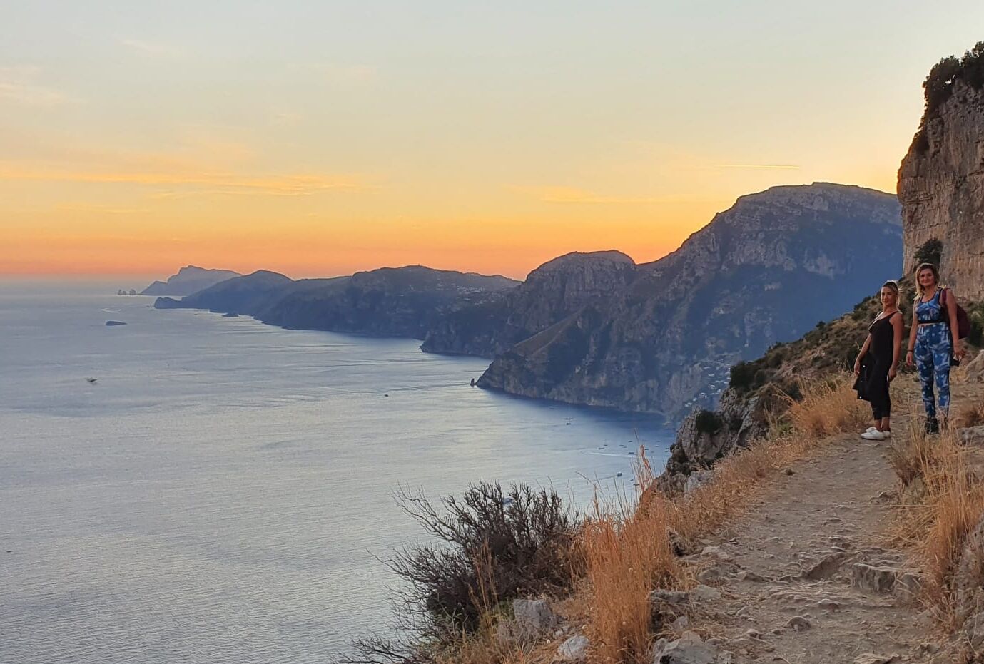 A coastal landscape with a clear view of the sea and distant mountains.