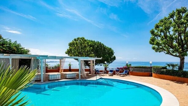 A swimming pool with a pergola, lounge chairs, and a view of the sea. - Villa Poseidon Boutique Hotel & Events (Salerno)