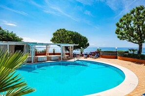A swimming pool with a pergola, lounge chairs, and a view of the sea. - Villa Poseidon Boutique Hotel & Events (Salerno)
