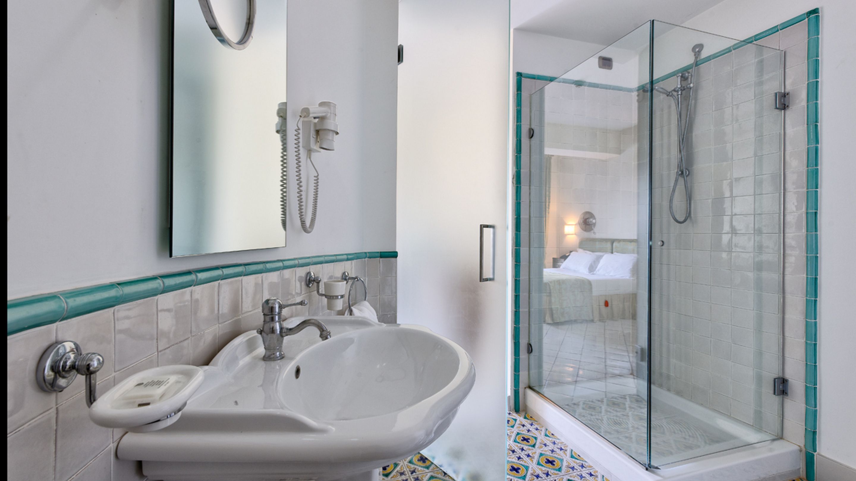 A bathroom with a sink, mirror, and shower.