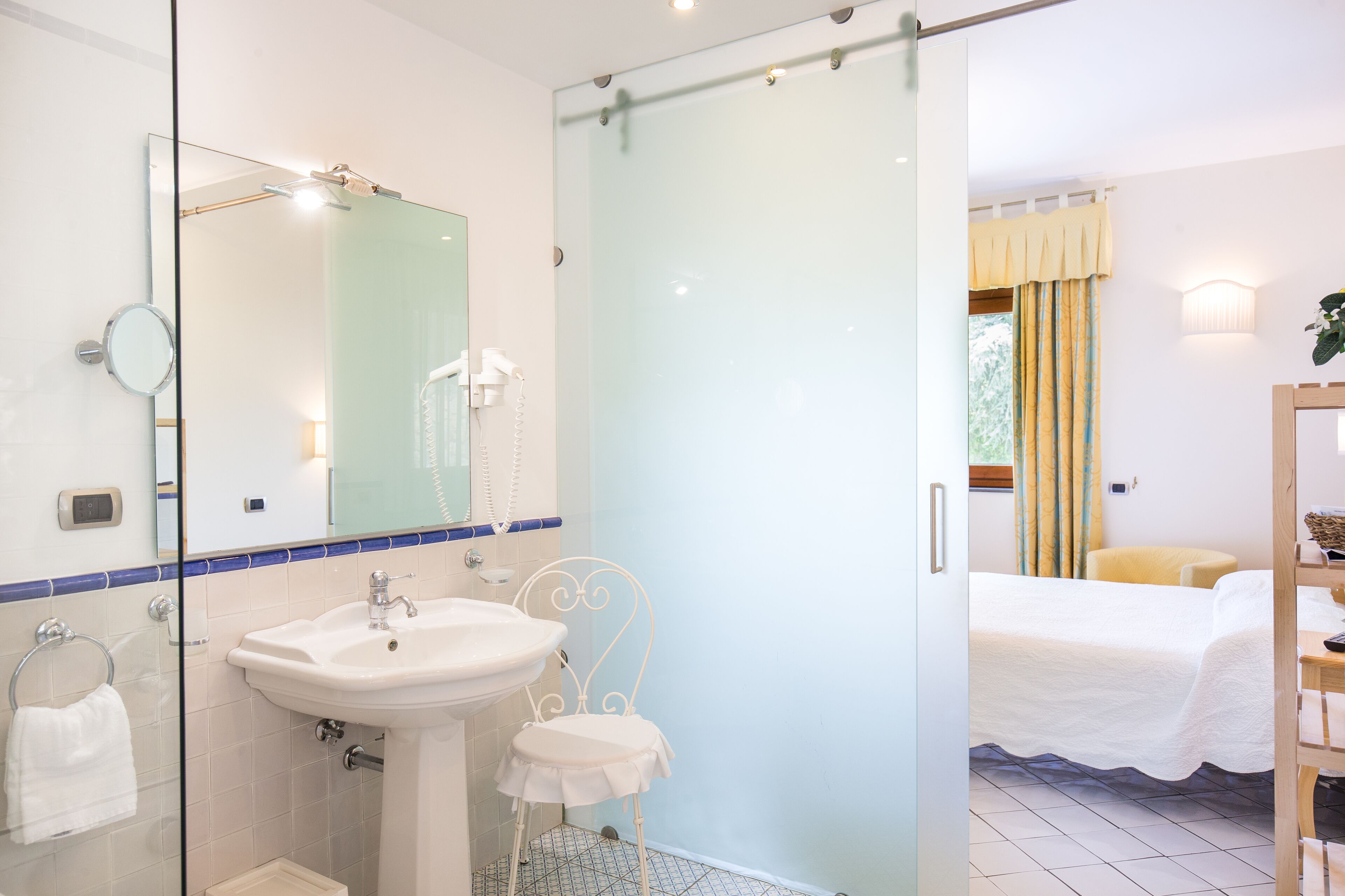 A bathroom with a glass shower enclosure, a sink, and a mirror.