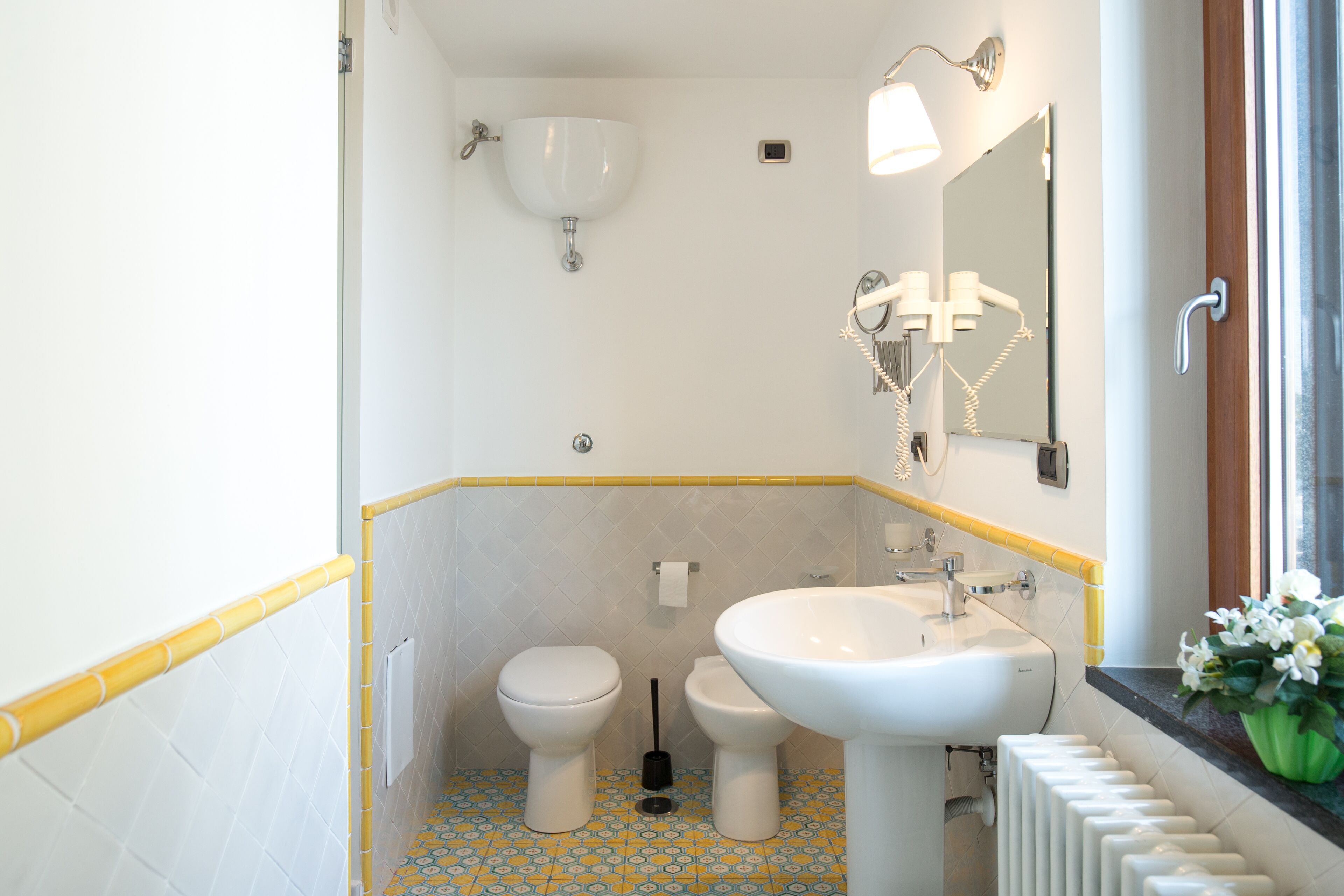 A bathroom with a toilet, bidet, sink, and a mirror.