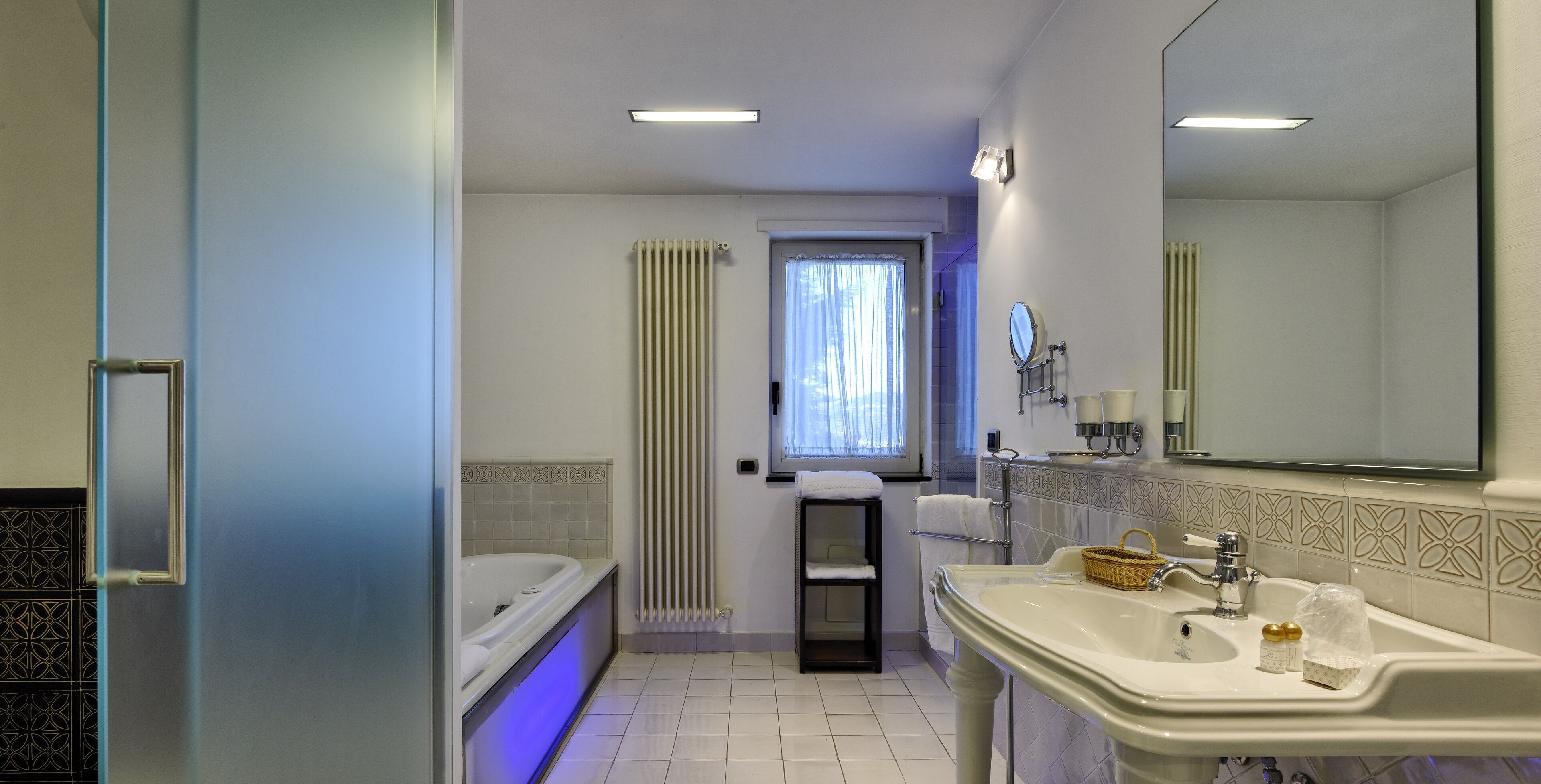 Ein Badezimmer mit Badewanne, Waschbecken, Spiegel und einem fenster mit Vorhängen.