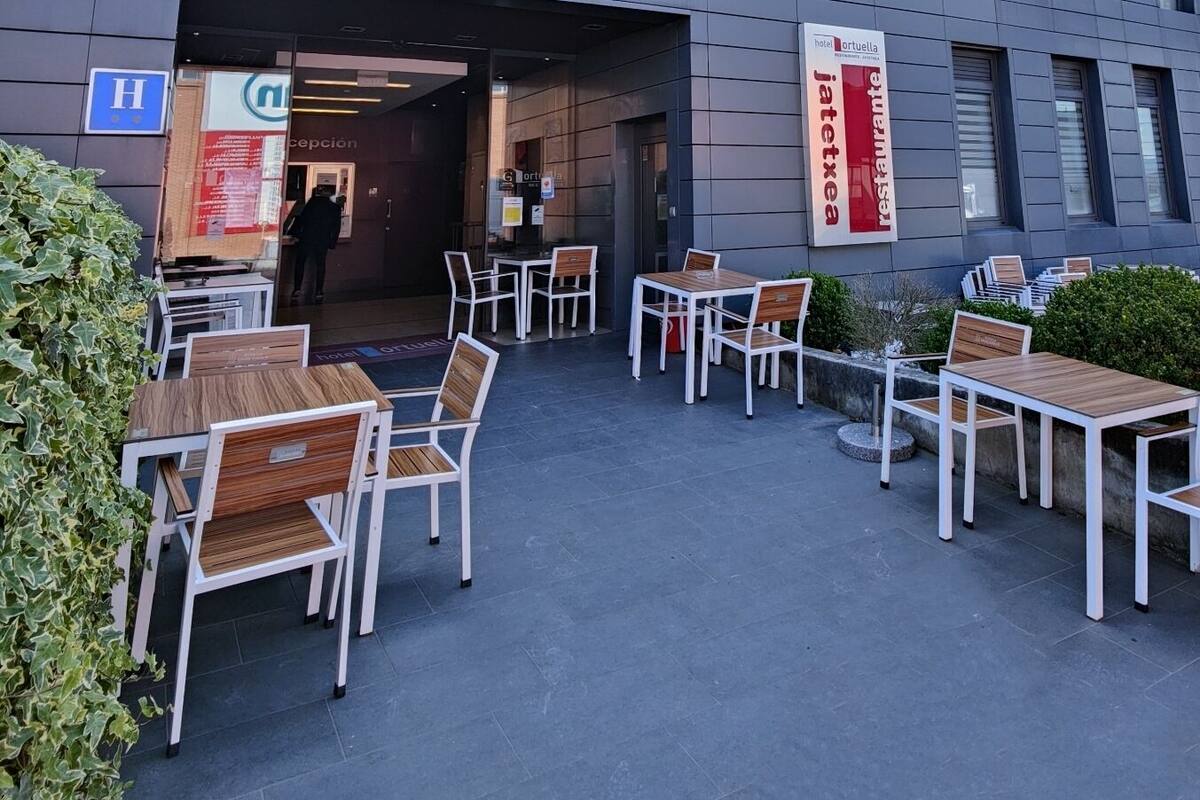A modern building with a reception area, outdoor seating, and a clear view of the sky.