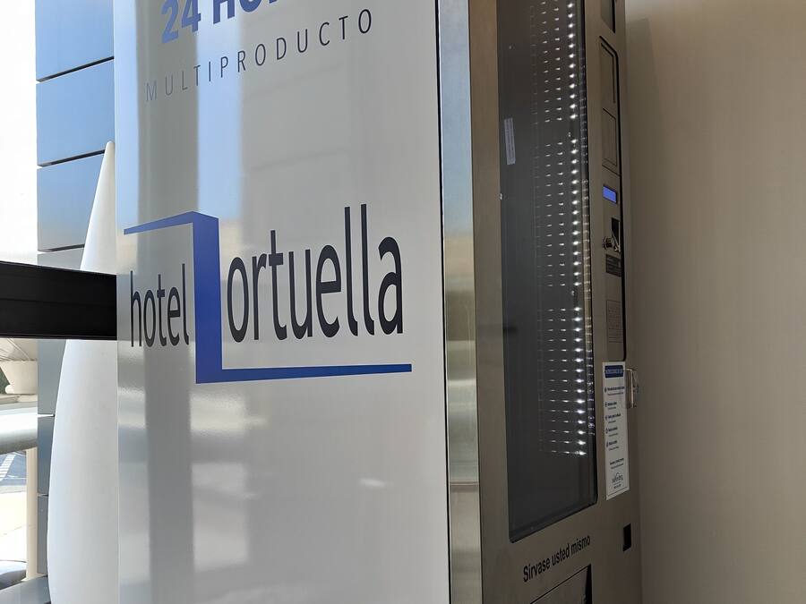 Una máquina expendedora de autoservicio con un letrero que indica que dispensa productos las 24 horas del día.