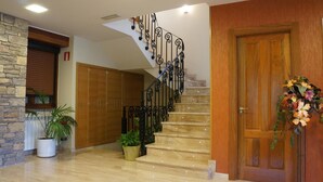 A staircase with a black iron railing, wooden doors, and potted plants. - Hotel Los Nogales (Campo)
