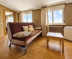 Una sala de estar moderna con un sofá marrón, cojines beige y una mesita blanca, además de un radiador.
