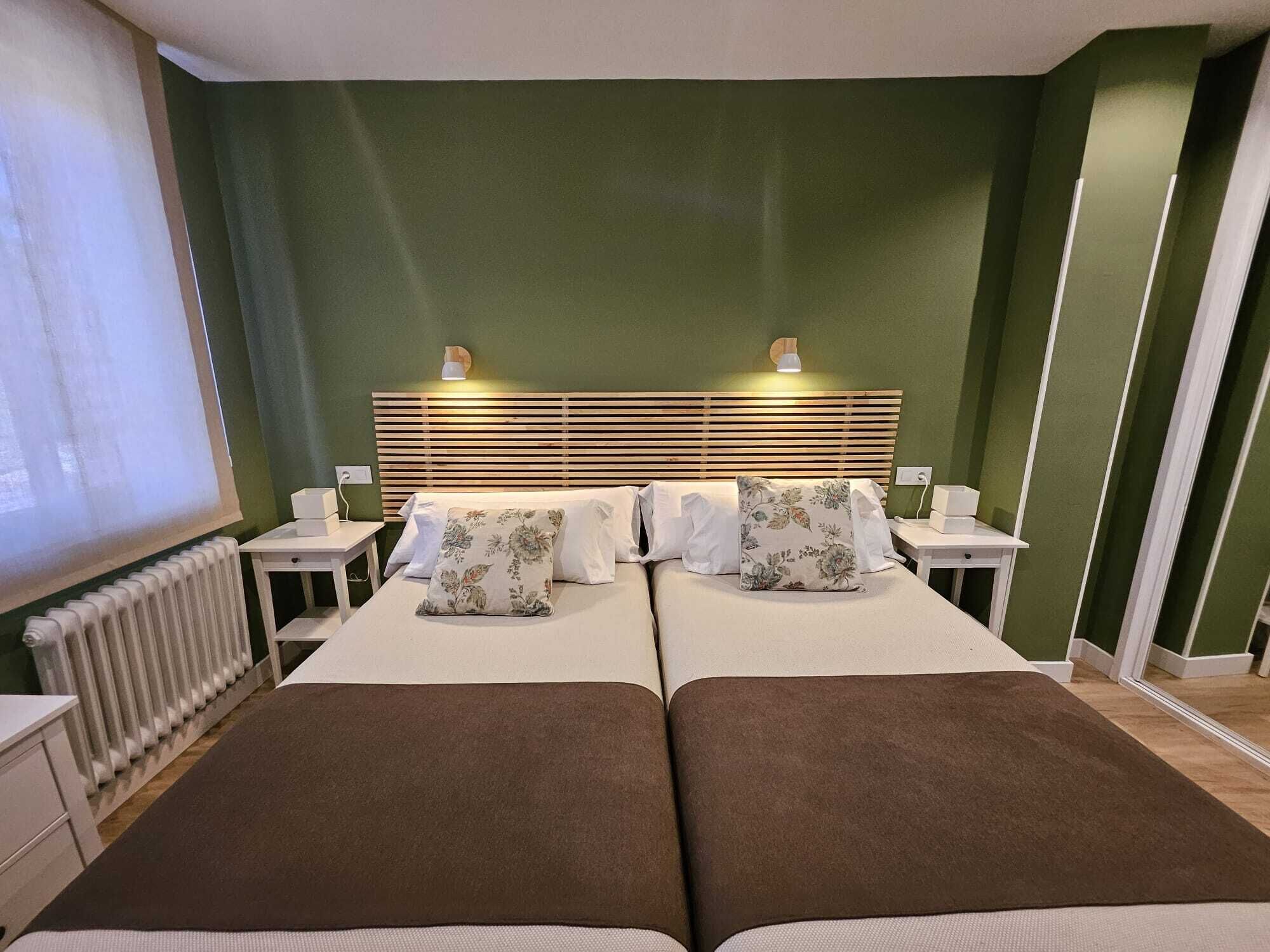 Un lit double avec une tête de lit en bois, deux tables de chevet et un radiateur.