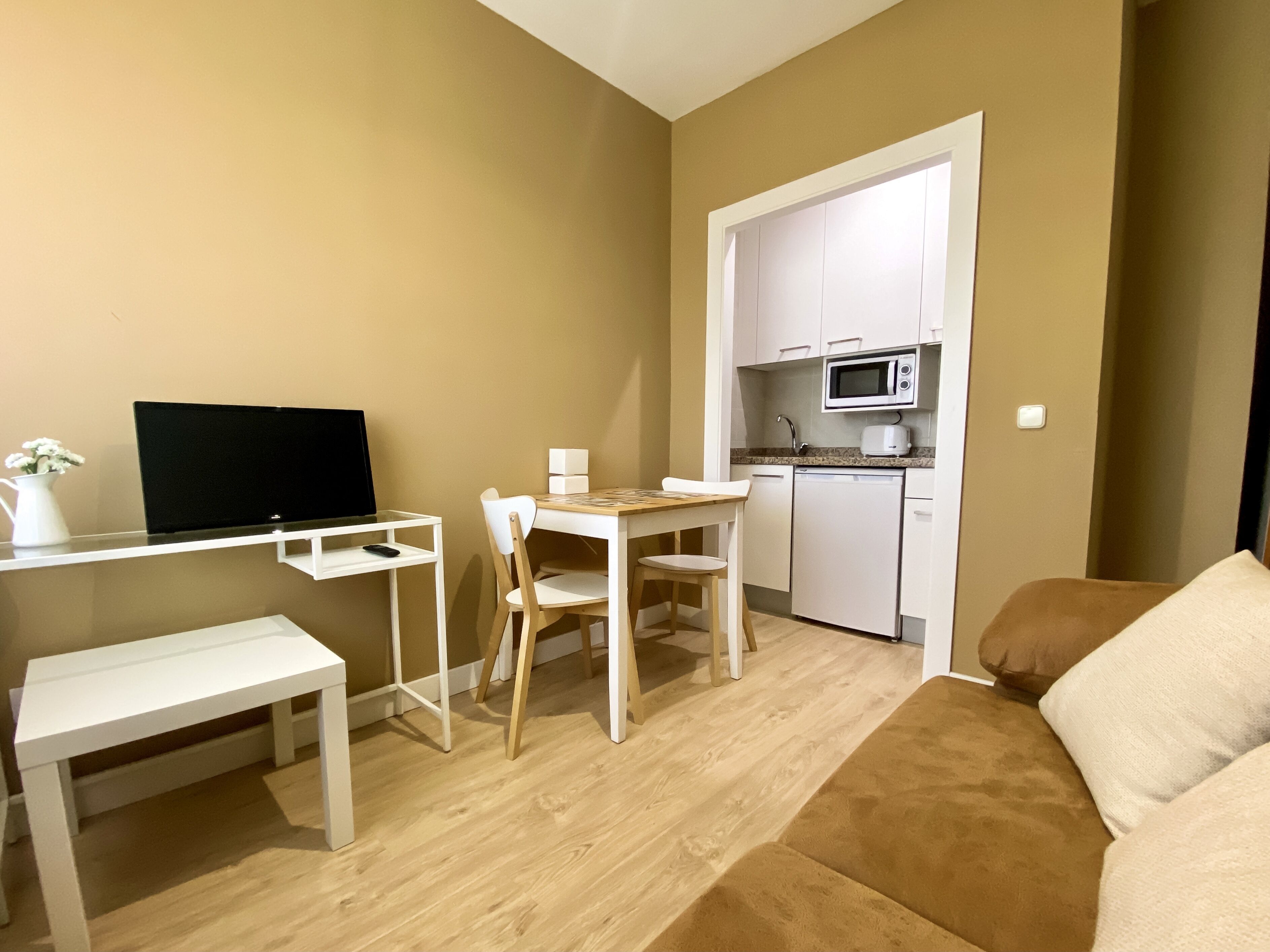 Espaço compacto com cozinha compacta, área de jantar com mesa e cadeiras, sofá e televisão de tela plana.