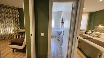 Une chambre d’hôtel avec un lit, une petite table, une chaise et une salle de bain équipée d’un lavabo et d’un miroir.